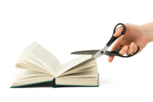 Hand with scissors cutting book